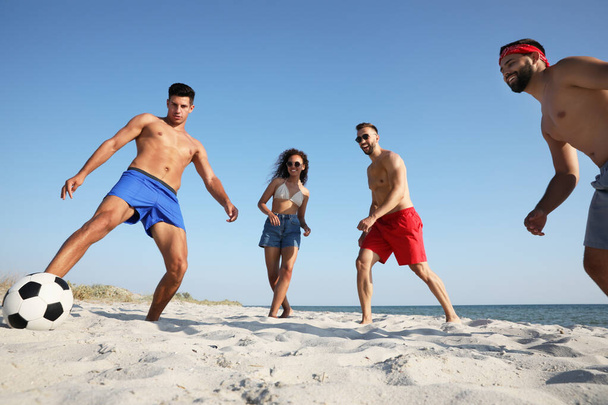 Group of friends playing football on beach - Fotó, kép