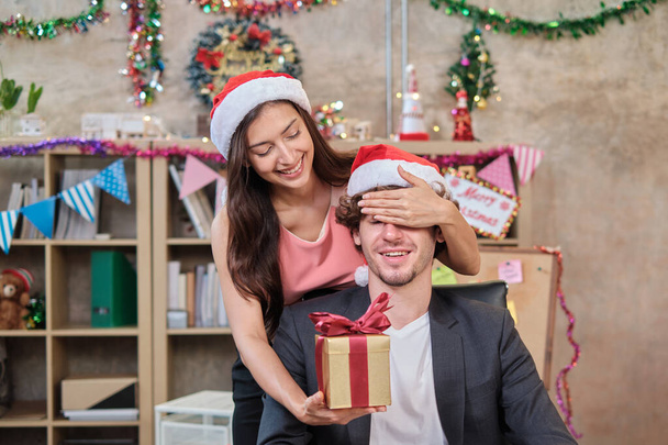 Yllätä kaksi työtoveria joukkue ja pomo antamalla lahjoja, kun liike-elämä työskentelee ennen yrityksen lomaa työpaikalla, on sisustettu joulujuhlaa ja uutta vuotta varten.. - Valokuva, kuva