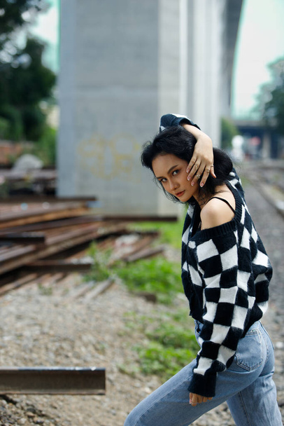Portrét 20s Asian Woman hnědé vlasy nosit bundu vysokou módní make-up pod modrým mrakem oblohy. Krásná žena vyjádřit pocit emoce úsměv šťastný nad vlakové koleje nádraží - Fotografie, Obrázek