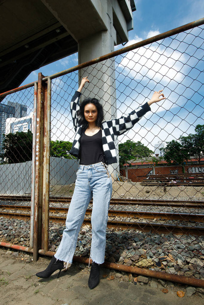 Portrait of 20s Asian Woman brown hair wear jacket high fashion make up under blue sky cloud. Beautiful female express feeling emotion smile happy over train track railroad station - Foto, Imagem