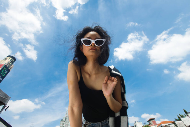 Portré 20-as ázsiai nő barna haj viselet kabát magas divat töltsük ki a kék ég felhő. Gyönyörű női kifejező érzés érzelem mosoly boldog, hajoljon le a kamera széles kilátás nyílik az égre - Fotó, kép