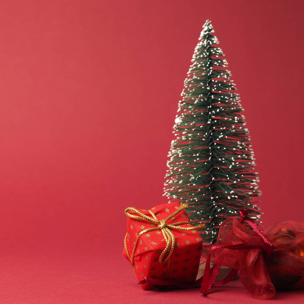 Scatola regalo di Natale rossa con fiocco dorato e decorazione su sfondo di carta rossa con spazio per testo o immagine - Foto, immagini