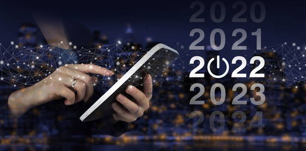 Neujahrskonzept. Ein weißes Tablet mit digitalem Hologramm auf dunklem Hintergrund. 2022 Neujahr. Konzeptstart ins neue Jahr 2022 - Foto, Bild