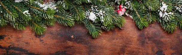 Christmas fir tree branch covered by snow on wooden background. Top view flat lay - Photo, Image