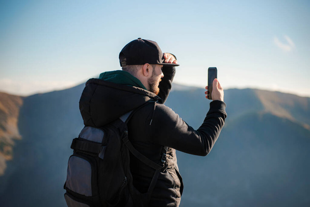 Όμορφος νεαρός άνδρας παίρνει ένα τοπίο στο βουνό smartphone. Κάσπροουι Γουίρτς. Πολωνία. - Φωτογραφία, εικόνα
