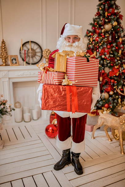 幸せなサンタクロースは子供たちに多くの贈り物をもたらしました。新年とメリークリスマスの休暇のコンセプト - 写真・画像