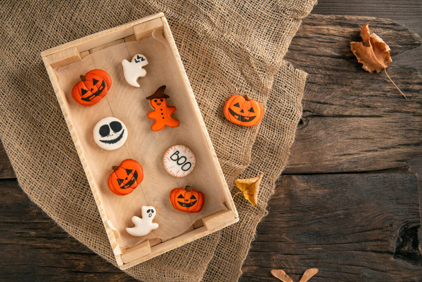 A mistura de biscoitos de gengibre brancos e cor-de-laranja para o Halloween é embalada em caixa de madeira e em mesa de madeira. Doces para o feriado. Foto de alta qualidade - Foto, Imagem