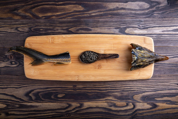 Lepel met zwarte kaviaar en gerookte steurvis op snijplank op houten ondergrond. Bovenaanzicht. Kopieerruimte. - Foto, afbeelding