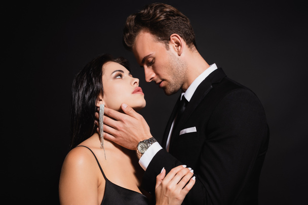 young man in elegant suit seducing stylish brunette woman isolated on black - Fotografie, Obrázek