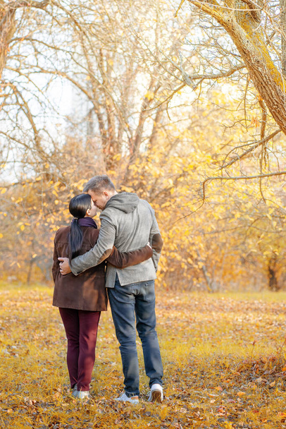 Autumn Caucasian Couple Standing Face-to-Face in a Park Full of Sun. Casual Style in Autumn Colors. Full-length. Fall Park Background - 写真・画像