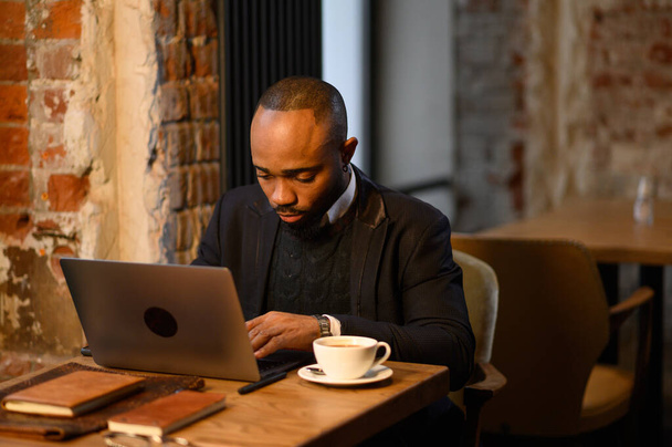 An African American student works at a laptop in a cafe - Foto, Imagem
