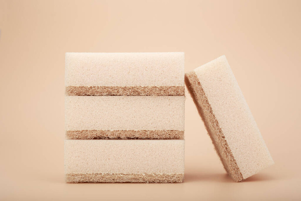 Beige cleaning and dishwashing sponges on beige background. Close up, dishwashing or house cleaning concept - Foto, afbeelding
