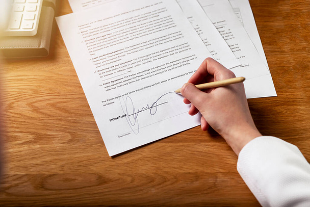 Contract signature concept. Female hand putting her sign on legal business agreement with pen - Photo, image