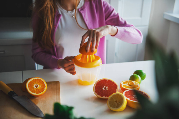 Donna che spremeva arance per fare un succo naturale di agrumi. routine mattutina. - Foto, immagini
