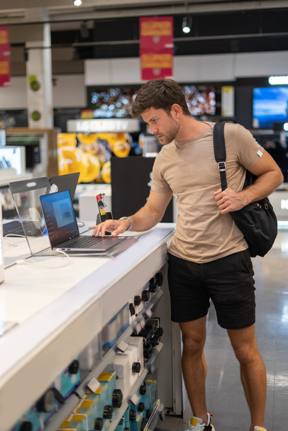 Uomo raccogliendo nuovo computer portatile in negozio - Foto, immagini