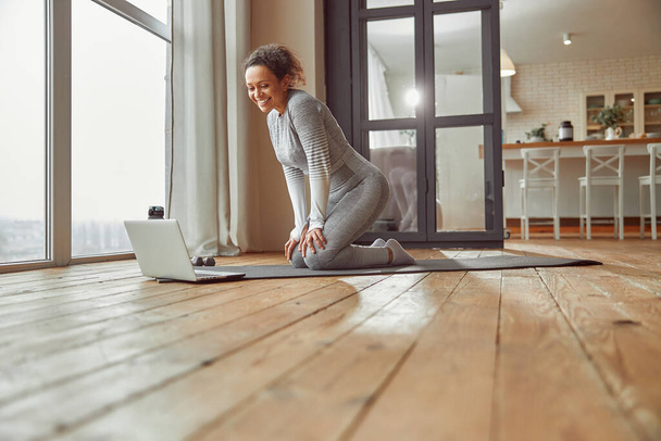 Счастливая женщина с ноутбуком, тренирующаяся в помещении - Фото, изображение