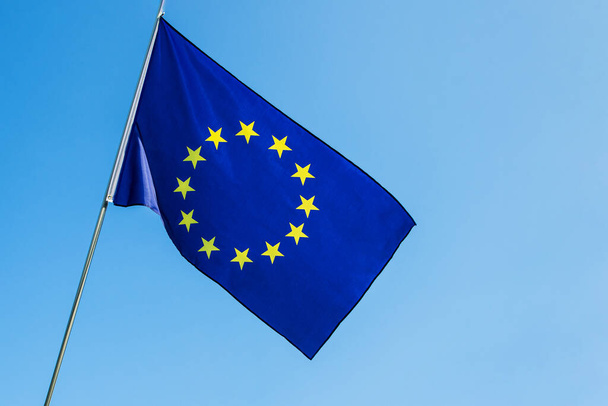 Флаг Европейского Союза размахивает ветром над голубым небом - Фото, изображение