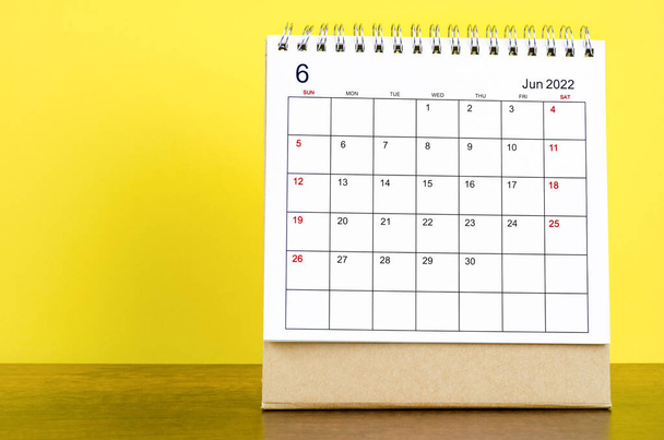 The June 2022 desk calendar with yellow background on the wooden table. - Foto, Bild
