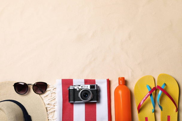 Beach towel, hat, sunglasses, camera, sunscreen and flip flops on sand, flat lay. Space for text - Φωτογραφία, εικόνα