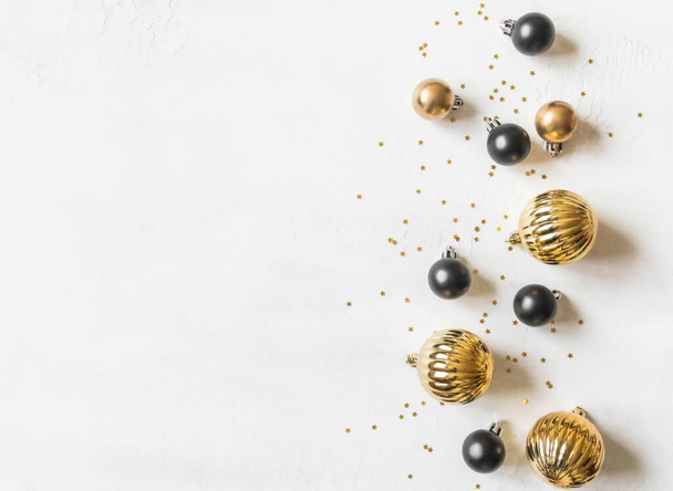 Greeting card - happy new year and Merry Christmas, gold stars glitter and black and gold christmas balls on white textured background. Minimal holiday concept. Top view. Flat lay - 写真・画像