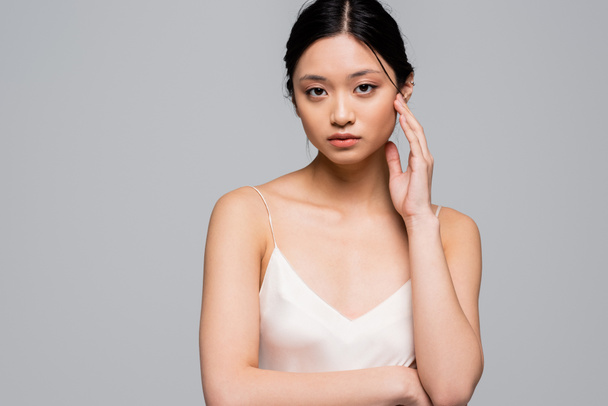 aziatische vrouw met perfect huid kijken naar camera geïsoleerd op grijs  - Foto, afbeelding