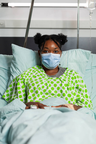 Portrait of sick young woman resting in bed during medical consultation - Photo, image