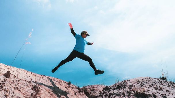 Male runner jumping on blue sky background, copy space - Photo, Image
