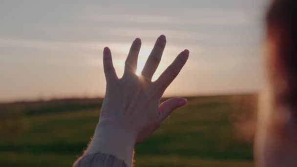 stretching girl hand forward at sunset in sky, praying to sun, traveling on a weekend vacation in rays of light, hiking in nature, relaxing rejoicing in glare of dawn, light through your fingers - Footage, Video