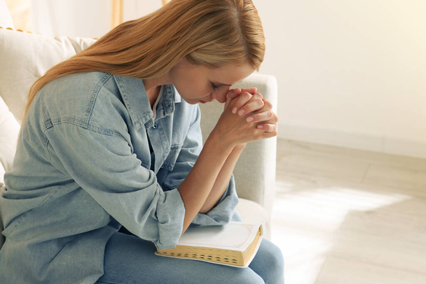 Religious young woman with Bible praying indoors. Space for text - Photo, image