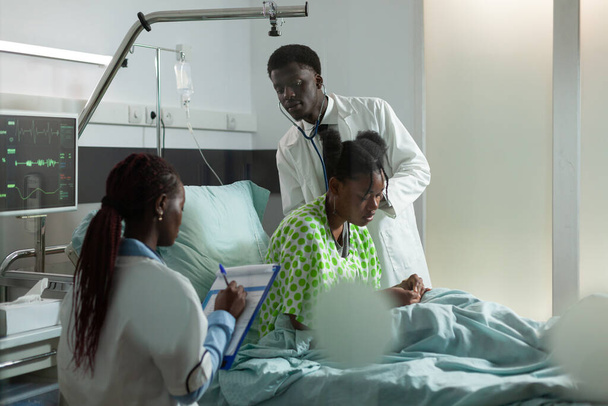 Afrikaanse Amerikaanse arts arts luisteren longen met behulp van stethoscoop - Foto, afbeelding
