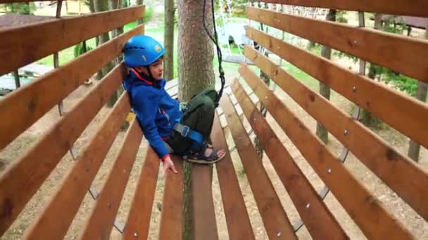 Boy in the climbing equipment took a break at the trail of the rope park. - Footage, Video
