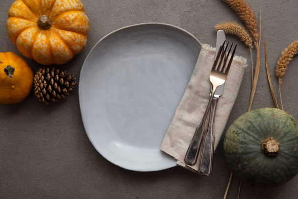 Overhead autumn thanksgiving dinner place setting with pumpkins cutlery and an empty plate - 写真・画像