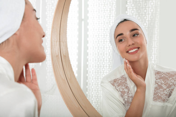 Beautiful young woman with perfect skin near mirror in bathroom. Facial wash - Foto, imagen