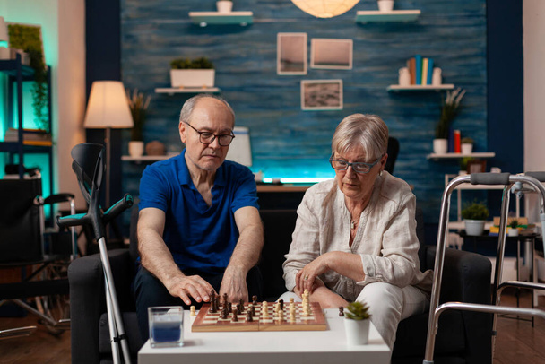Παντρεμένο ηλικιωμένο ζευγάρι που παίζει σκάκι στο πλοίο στο σπίτι - Φωτογραφία, εικόνα