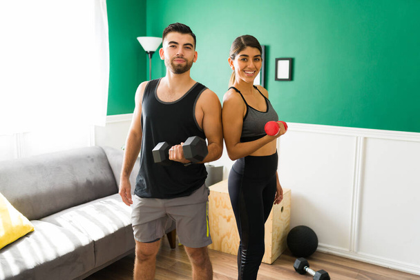 Здоровий підходить жінка і чоловік посміхається і робить зоровий контакт під час підйому ваги для підтримки свого спортивного тіла
 - Фото, зображення
