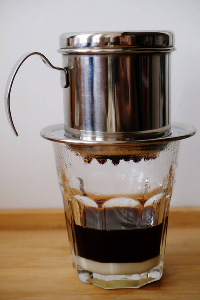 Сварка кофе в вьетнамском фине с сгущенным молоком в стакане. - Фото, изображение