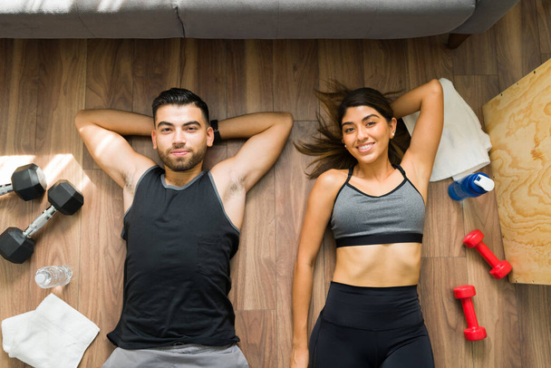 Horní pohled na fitness pár odpočívající na podlaze po dokončení jejich cvičení s závažími  - Fotografie, Obrázek