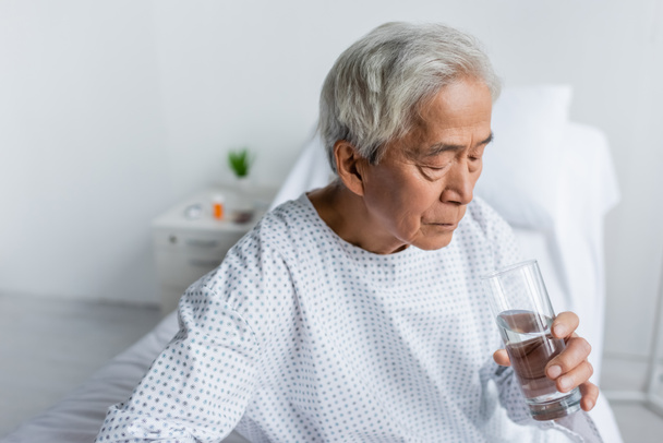 Anziani asiatico paziente holding bicchiere di acqua in ospedale reparto  - Foto, immagini