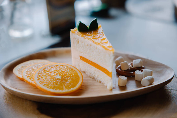 Orange cake dessert on a wooden plate in the restaurant - Foto, Imagem