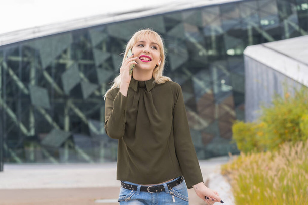 Enterprising Caucasian blonde girl in business park making work call, modern workplace among nature - Φωτογραφία, εικόνα