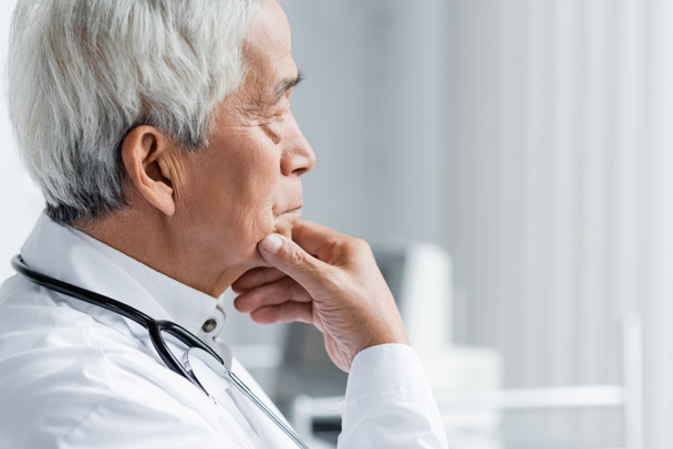 Side view of senior asian doctor looking away in clinic  - Foto, Bild