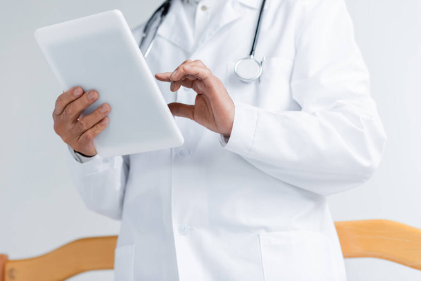 Vue recadrée du médecin en manteau blanc à l'aide d'une tablette numérique en clinique  - Photo, image