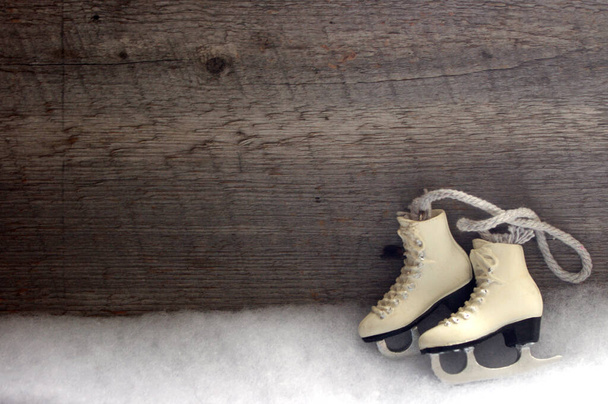 Biała figurka łyżwy ozdoba na białym śniegu z rustykalnym drewnianym tle i przestrzeń kopiowania - Zdjęcie, obraz
