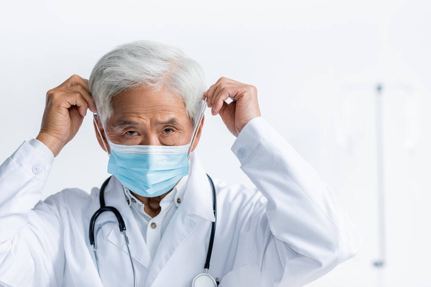 Senior asian doctor wearing medical mask in clinic  - Photo, image