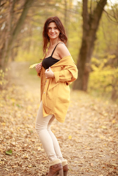 Uma bela jovem caminha ao longo de uma trilha na floresta, outono folhas secas no chão, queda de folhas, novembro. - Foto, Imagem
