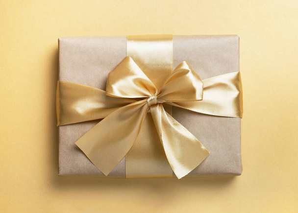 Κουτί δώρου με φιόγκο σε χρυσό φόντο. Χριστούγεννα, Πρωτοχρονιά ή δώρο γενεθλίων. Πάνω άποψη, επίπεδη lay - Φωτογραφία, εικόνα