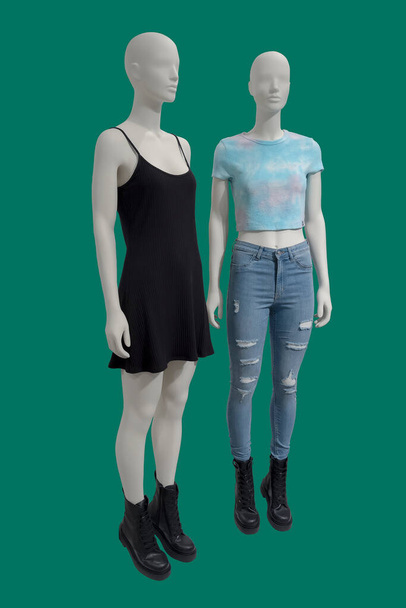 Twee volledige beelden van een vrouwelijke etalagepoppen dragen modieuze kleding geïsoleerd op een groene achtergrond  - Foto, afbeelding
