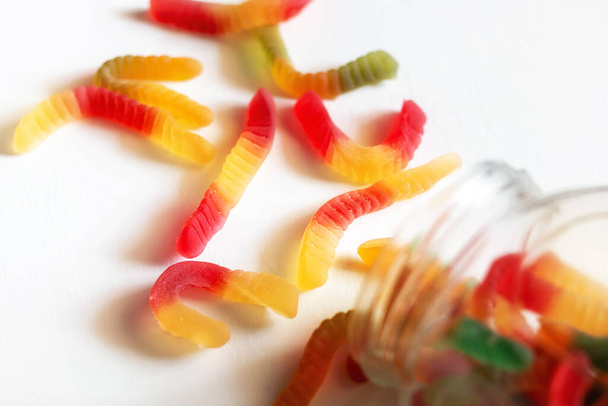 multicolored gummy jelly worms candy and glass jar on white background - Zdjęcie, obraz