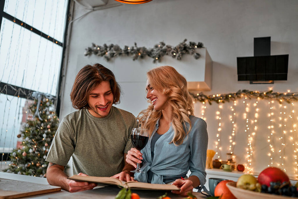 Portrait of a couple having a glass of red wine while cooking Christmas supper. Front view - Foto, imagen