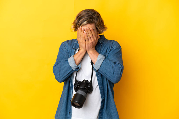 Young photographer man isolated on yellow background with tired and sick expression - Fotó, kép
